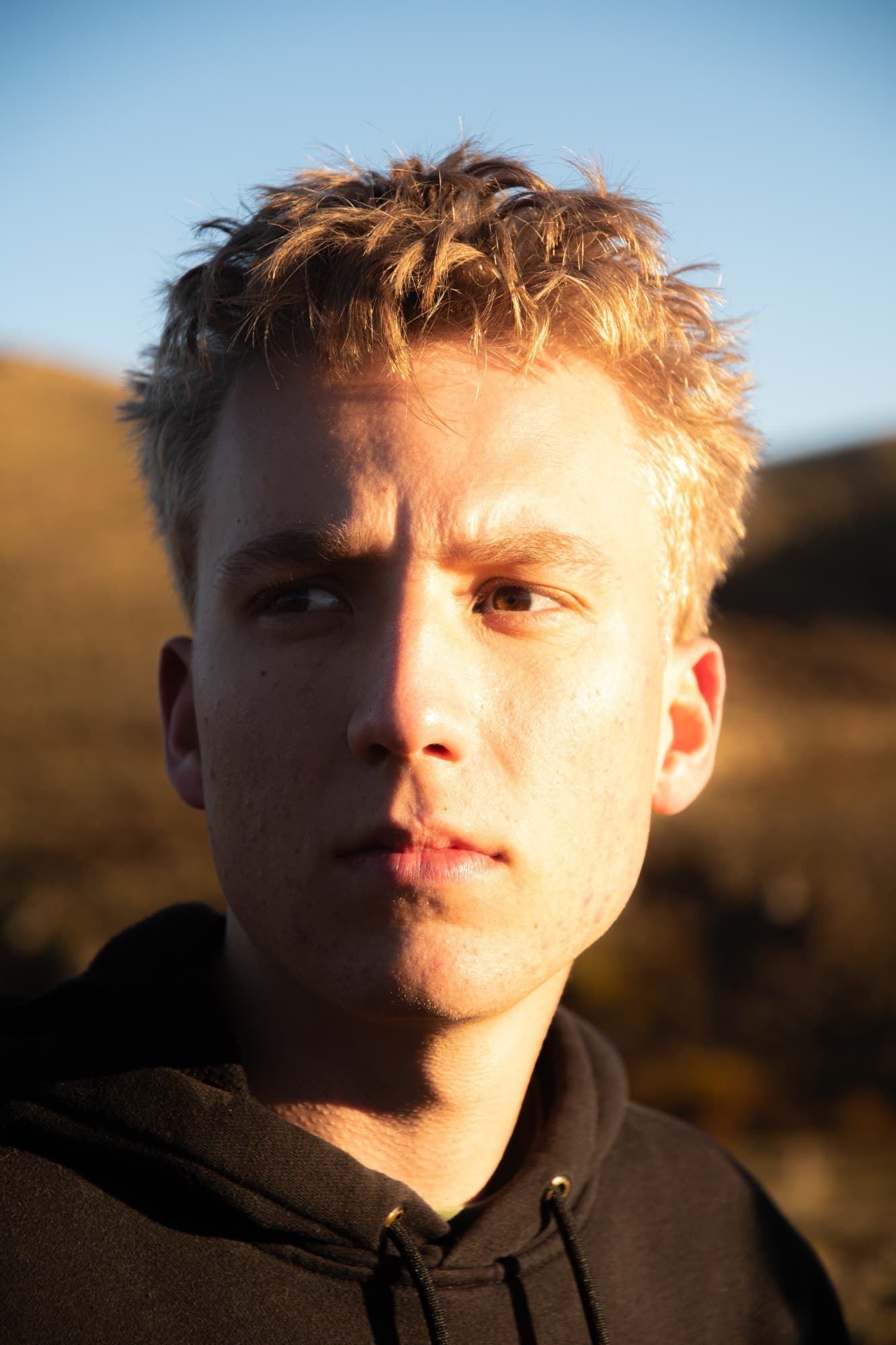 Portrait of Russell in warm golden-hour light against a clear blue sky